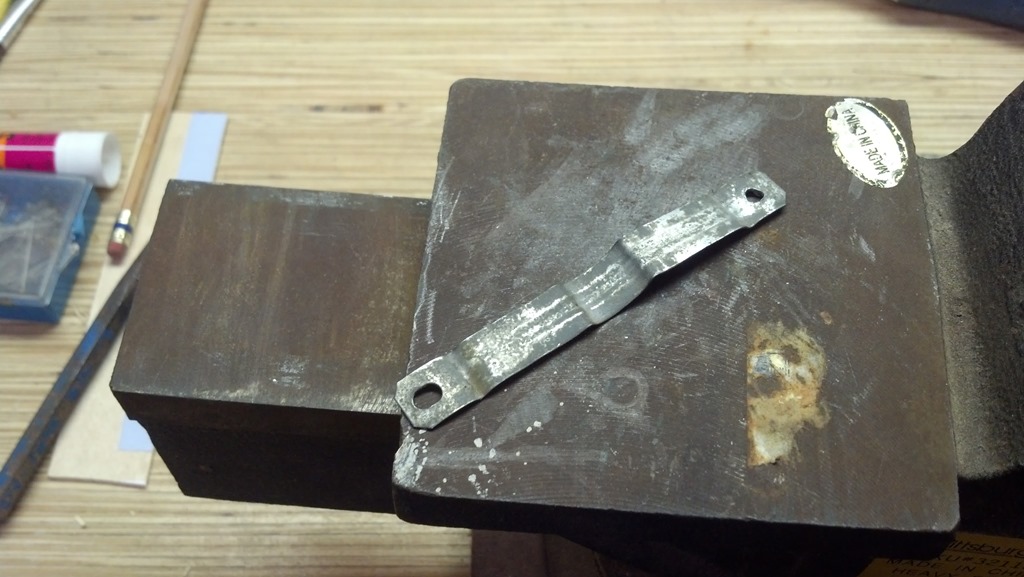 thin metal strip being hammerd flat on an metal vise