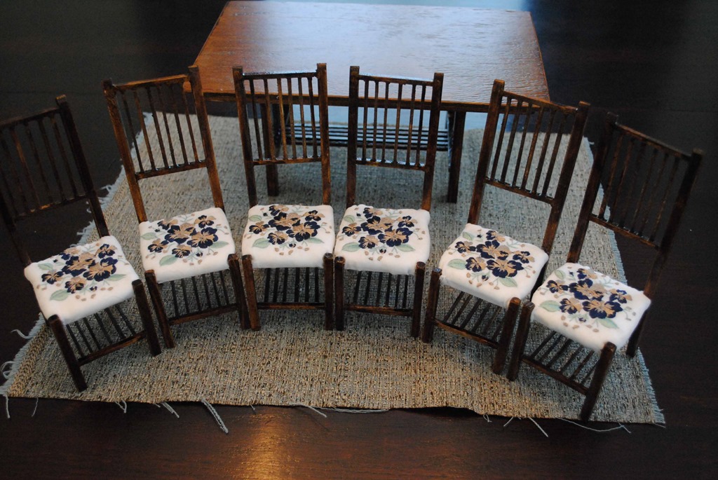 Six model chairs with embroidered cushions